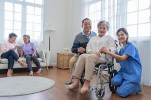 asiatisch jung Krankenschwester Unterstützung Paar Senior älter Mann und Frau im ein Rollstuhl. Alten reifen und ein Gruppe von Senior freunde Leben im das Krankenhaus. Geselligkeit von im Ruhestand Personen. foto