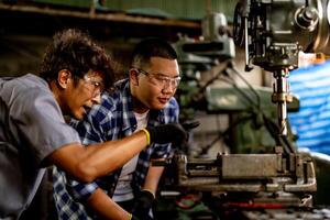 asiatisch Arbeiter im Produktion Pflanze Bohren beim Maschine. Fachmann Arbeiter in der Nähe von Bohren Maschine auf Fabrik. Fertigstellung Metall Arbeiten intern Stahl Oberfläche auf Drehbank Schleifer Maschine mit fliegend Funken. foto