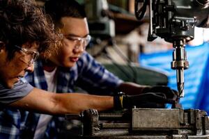 asiatisch Arbeiter im Produktion Pflanze Bohren beim Maschine. Fachmann Arbeiter in der Nähe von Bohren Maschine auf Fabrik. Fertigstellung Metall Arbeiten intern Stahl Oberfläche auf Drehbank Schleifer Maschine mit fliegend Funken. foto