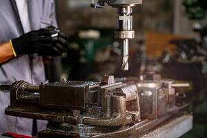 Ingenieur Arbeiter im Produktion Pflanze Bohren beim Maschine. Fachmann Arbeiter in der Nähe von Bohren Maschine auf Fabrik. Mann inspizieren und reparieren Maschine zum Betrieb im Werkstatt. foto