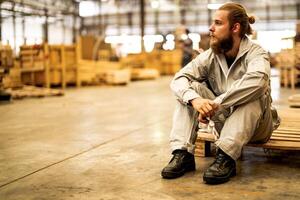 Mann Arbeitskräfte Ingenieurwesen Sitzung mit Vertrauen mit Arbeiten Suite Kleid und Hand Handschuh im Vorderseite Maschine. Konzept von Clever Industrie Arbeiter Betriebs. Holz Fabrik produzieren Holz Gaumen. foto