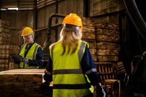 Mannschaft Arbeiter Zimmermann tragen Sicherheit Uniform und schwer Hut Arbeiten und Überprüfung das Qualität von hölzern Produkte beim Werkstatt Herstellung. Mann und Frau Arbeitskräfte Holz im dunkel Warenhaus Industrie. foto