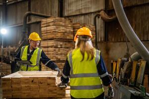 Mannschaft Arbeiter Zimmermann tragen Sicherheit Uniform und schwer Hut Arbeiten und Überprüfung das Qualität von hölzern Produkte beim Werkstatt Herstellung. Mann und Frau Arbeitskräfte Holz im dunkel Warenhaus Industrie. foto