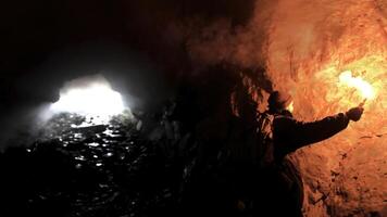 einsam Mann mit ein rot Verbrennung Signal Fackel im ein dunkel Höhle suchen zum das Loch, Tourismus Konzept. Lager Filmaufnahme. männlich erkunden unter Tage Höhle. foto