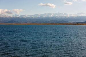 Blau Ruhe Wasser im issyk-kul See mit Berge auf Hintergrund beim Herbst Nachmittag foto