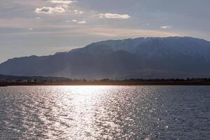 Blau Ruhe Wasser im issyk-kul See mit Berge auf Hintergrund beim sonnig Herbst Abend foto