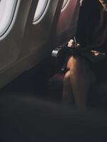 blond weiblich Tourist Überprüfung eingehend Benachrichtigung auf Smartphone Sitzung auf Sitz von Flugzeug mit Netbook.jung Geschäftsfrau Teilen Medien von Telefon auf Laptop Computer während Flugzeug Flug foto