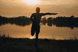 zurück Aussicht Silhouette von ein Läufer Mann Laufen auf das Strand beim Sonnenuntergang mit Sonne im das Hintergrund foto