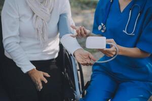 Krankenschwester mit Alten Mann im Rollstuhl beim Park foto