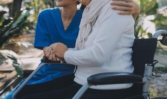 ein Krankenschwester nehmen Pflege ein Senior männlich auf Rollstuhl im seine Garten beim Zuhause foto