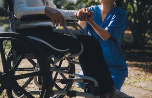 Pflege- Mitarbeiter reden zu ein Alten Person Sitzung im ein Rollstuhl. foto