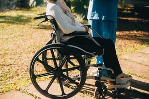 Pflege- Mitarbeiter reden zu ein Alten Person Sitzung im ein Rollstuhl. foto