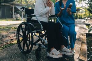 Krankenschwester mit Alten Mann im Rollstuhl beim Park foto