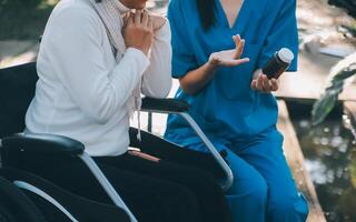 Krankenschwester mit Alten Mann im Rollstuhl beim Park foto