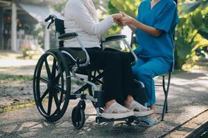 ein Krankenschwester nehmen Pflege ein Senior männlich auf Rollstuhl im seine Garten beim Zuhause foto