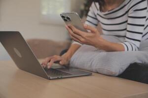 glück unternehmer schönes geschäft asiatische junge frau tragen lässiges handy zum online einkaufen genießen sie mit social media und laptop zu hause. kleinunternehmen startup. online banking foto