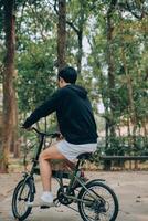 gut aussehend glücklich jung Mann mit Fahrrad auf ein Stadt Straße, aktiv Lebensstil, Menschen Konzept foto