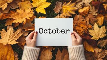ai generiert Hände halten ein Blatt von Papier mit das Wort Oktober im Herbst Blätter Hintergrund foto
