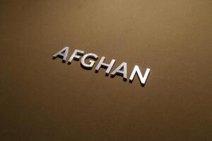 das wort afghanisch mit silbernen metallbuchstaben auf rauem khakifarbenem canvas-stoff foto