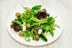 Salat Blätter mit Rucola, Käse, Grün Oliven im ein Platte, gesund Diät Salat. foto