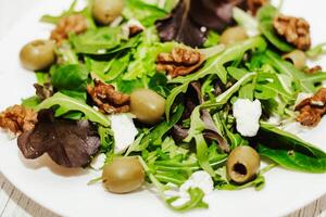 Salat Blätter mit Rucola, Käse, Grün Oliven und Nüsse im ein Platte, gesund Diät Salat foto