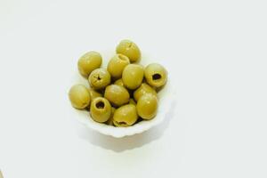Grün Dosen- Oliven im ein Weiß Schüssel auf das Tisch. foto