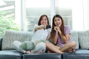 asiatisch Frau und Freund sitzen beim Zuhause auf Sofa Bett Uhr Fernseher Film. foto