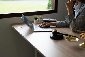 Gerechtigkeit und Gesetz konzept.männlich Richter im ein Gerichtssaal auf hölzern Tabelle und Berater oder Nahansicht Anwalt Arbeiten mit lsptop im Büro. legal Gesetz, Rat und Gerechtigkeit Konzept. foto