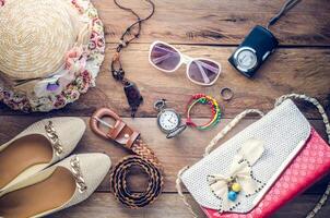 Zubehör zum Teenager Mädchen auf ihr Urlaub, Hut, stilvoll zum Sommer- Sonnenbrille, Leder Tasche, Schuhe und Kostüm auf hölzern Fußboden foto