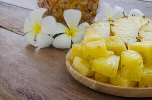 geschnitten Ananas auf hölzern Teller dekoriert mit schön Blumen. foto