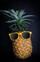 Ananas Sonnenbrille ruhen auf das schwarz Hintergrund Konzept zum Reise. foto