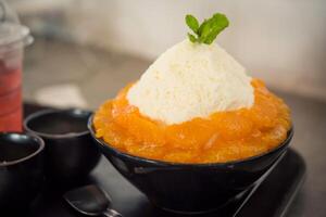 Nahansicht Orange Bingsu gekrönt mit Käse und Joghurt Eis Bingsoo ist ein Koreanisch rasiert Eis Dessert mit Süss ausgepeitscht Sahne und gesüßt kondensiert Milch. es ist sehr Beliebt Nachtisch. foto