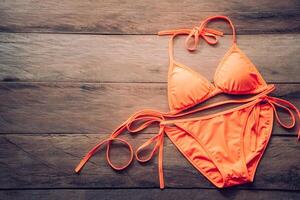 Orange Bikini ruht auf ein hölzern Fußboden -Sommer und Reise cocept. foto