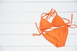 Orange Bikini ruht auf ein hölzern Fußboden -Sommer und Reise cocept. foto