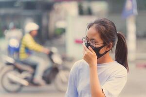 Mädchen tragen ein schwarz Nasen n95 Stoff zu verhindern Staub Uhr 2.5 welche hat ein sehr hoch Wert im ein Stadt mit der Verkehr foto