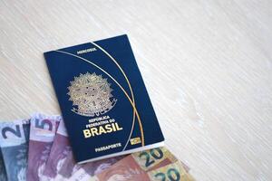 Reisepass Buch von föderativ Republik von Brasilien und Brasilianer reais Geld Rechnungen auf hölzern Hintergrund foto