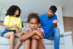 Familie Missverständnis, Kindheit Probleme. traurig beleidigt schwarz Tochter Sitzung auf das Boden, drehen zurück zu Eltern nach Streit beim heim, verärgert Mama und Papa fragen ärgerlich Mädchen was ist falsch foto