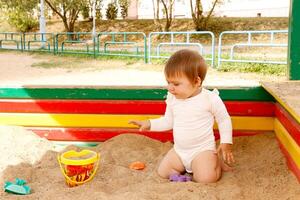 Baby Mädchen spielen im das Sandkasten foto