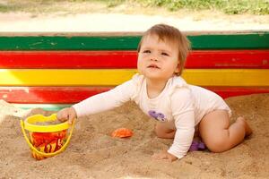 Baby Mädchen spielen im das Sandkasten auf das Spielplatz auf ein Sommer- sonnig Tag foto