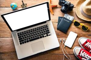 Laptop und Reise Zubehör Kostüme Tourismus Planung und Ausrüstung erforderlich zum das Ausflug auf hölzern Fußboden foto