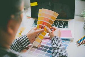 das Grafik Designer kreativ Mannschaft ist zur Zeit Arbeiten auf das Design und Farbe Auswahl auf das leiten Farbe zum Werbung Design. foto