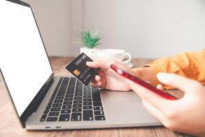 frauenhände, die eine kreditkarte halten und an laptop-online-zahlung für online-einkäufe arbeiten foto