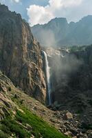 ai generiert Magier erfasst mächtig Wasserfall Kaskadierung Nieder robust, felsig Berg Cliff. das Himmel über ist teilweise wolkig Anzeige Leben inmitten das felsig Terrain ai generiert foto