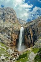 ai generiert Magier erfasst mächtig Wasserfall Kaskadierung Nieder robust, felsig Berg Cliff. das Himmel über ist teilweise wolkig Anzeige Leben inmitten das felsig Terrain ai generiert foto