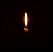 ein Single Verbrennung Kerze Flamme oder Licht glühend auf ein Orange Kerze auf schwarz oder dunkel Hintergrund auf Tabelle im Kirche zum Weihnachten, Beerdigung oder Denkmal Bedienung mit Kopieren Raum foto