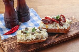 Bruschetta mit Weichkäse, Kapern und Tomate foto