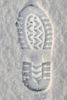 Nahansicht von ein Schuh drucken im das Schnee, oben Aussicht von ein Stiefel Fußabdruck foto