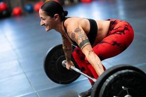 lächelnd reifen sportlich Frau Gewichtheben im ein Fitnessstudio foto