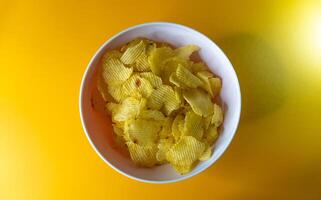 Nahansicht von Kartoffel Chips oder Kartoffelchips im Schüssel gegen Gelb Hintergrund foto