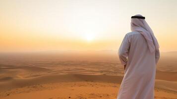 ai generiert Arabisch Mann Stehen im das Wüste und suchen beim das Sonnenuntergang. foto